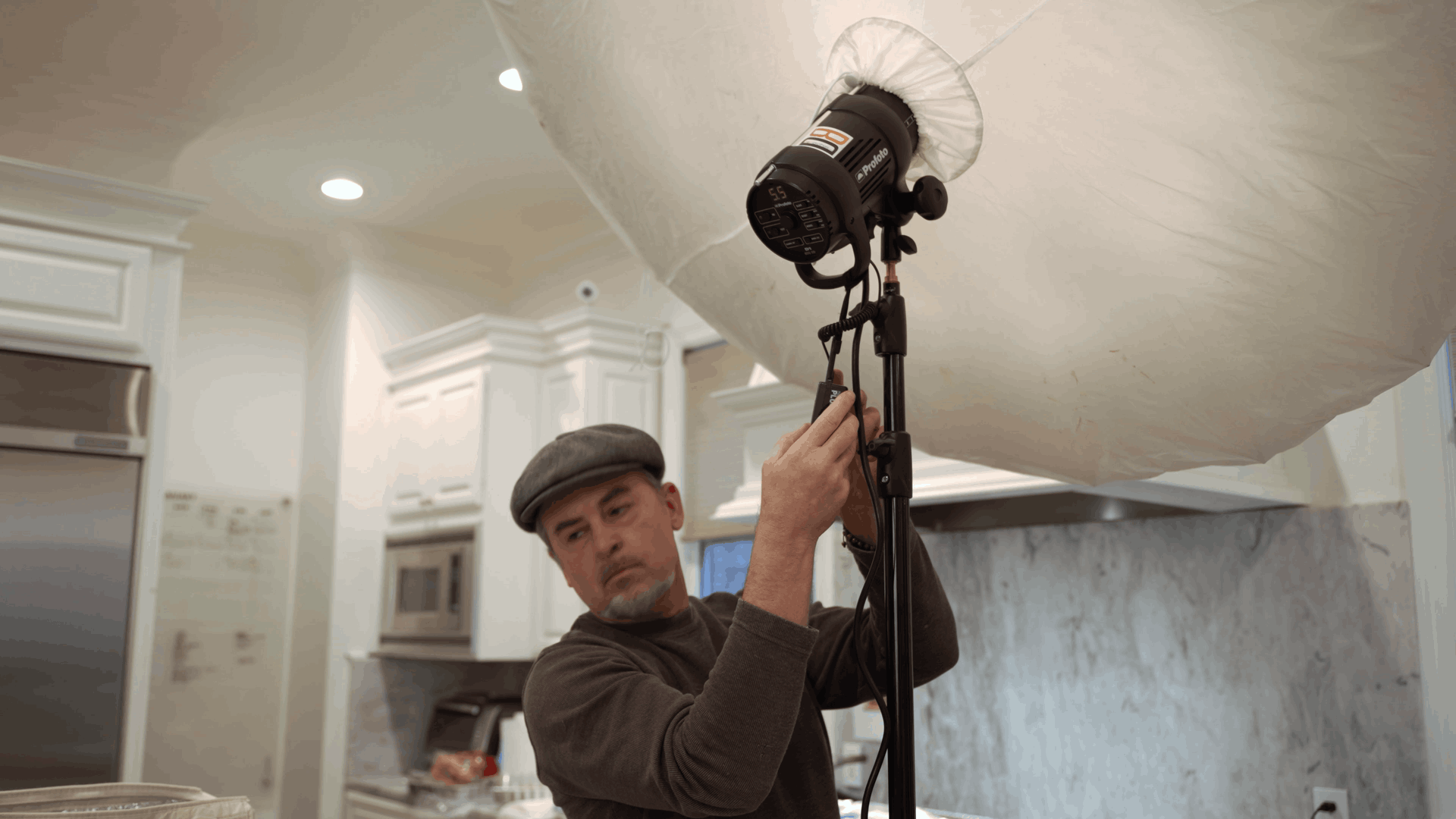 A professional food photographer setting up studio lighting in a kitchen for the burger photoshoot.